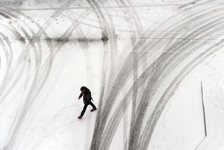 A pedestrian goes between the maze of tire tracks in the snow Tuesday afternoon, Feb. 4, 2014, at the downtown parking garage. Kentucky is bracing for more snow in the west and ice through other parts of the state as the latest winter blast moves through. (AP Photo/The Messenger-Inquirer, John Dunham,)