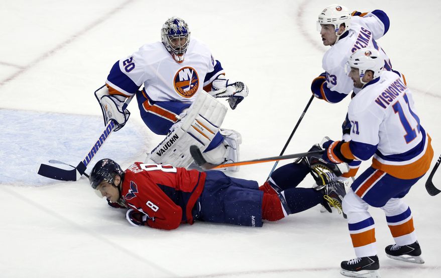 Washington Capitals right wing Alex Ovechkin (8), from Russia, slides by goalie Evgeni Nabokov (20), from Russia, after being tripped by defenseman Lubomir Visnovsky (11), from Slovakia, with center Casey Cizikas (53), in the third period of an NHL hockey game, Tuesday, Feb. 4, 2014, in Washington. Visnovsky was penalized for tripping on the play. The Islanders won 1-0. (AP Photo/Alex Brandon)