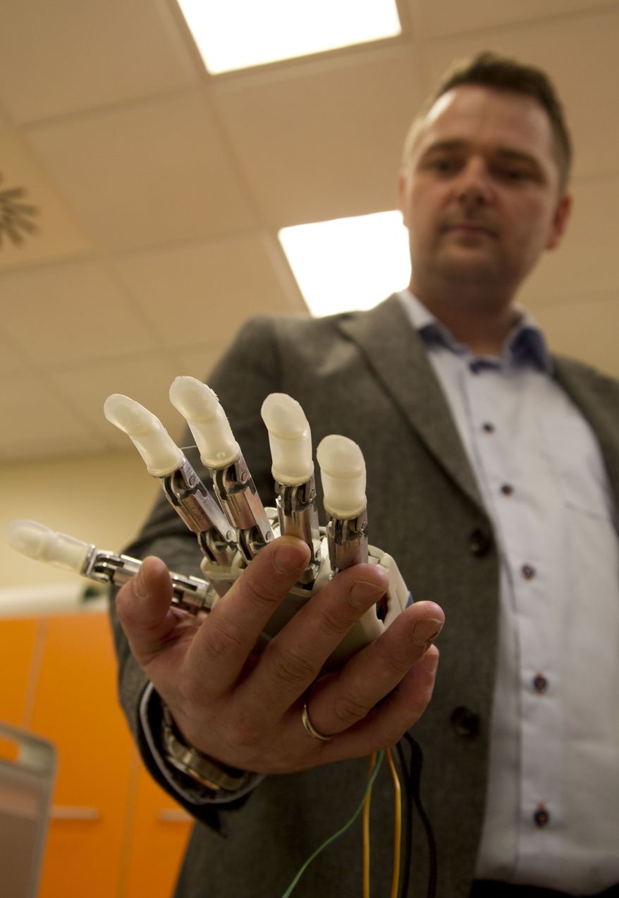 Dennis Aabo Sørensen, of Aalborg, Denmark, who lost his left hand in a fireworks accident a decade ago, shows the sensory feedback enabled prosthesis he is testing in Rome, Wednesday, Feb. 5, 2014. The patient only got to experiment with the bulky prototype for a week, and it's far from the bionics of science fiction movies. But the research released Wednesday is part of a major effort to create more lifelike, and usable, prosthetics. This isn't the first time scientists have tried to give some sense of touch to artificial hands; a few other pilot projects have been reported in the U.S. and Europe. But this newest experiment, published in the journal Science Translational Medicine, shows Sorensen not only could tell differences in the shape and hardness of objects, he also could quickly react and adjust his grasp. (AP Photo/Paolo Santalucia)