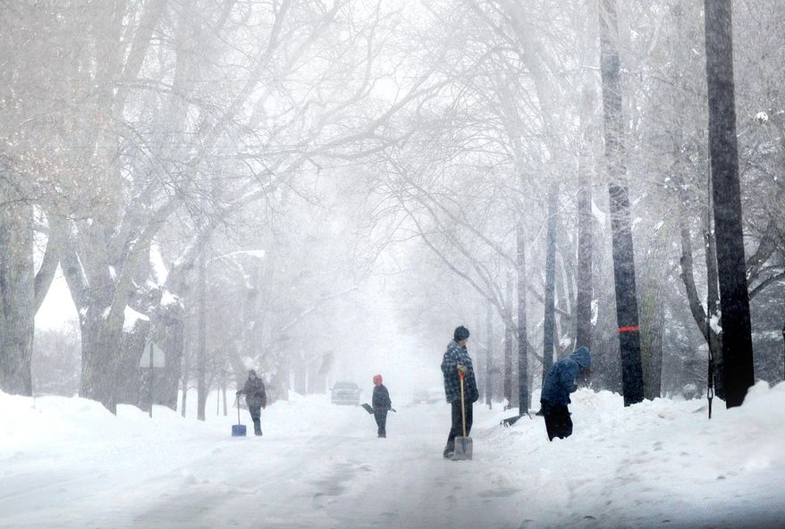 Residents, with shovels in hand, work to clear North Roessler Street and their walkways as heavy snow continues to fall throughout the region in Monroe, Mich., Wednesday, Feb. 5, 2014. (AP Photo/Monroe News, Kim Brent)