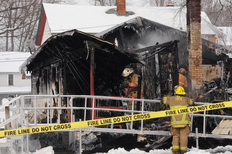 Firefighters work the scene of a house fire along North Elm Street in Three Oaks, Mich., Thursday, Feb. 6, 2014, which left four people dead. The village fire department and state fire marshal's office were investigating. (AP Photo/The Herald-Palladium, Don Campbell)