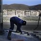 A construction worker removes paving bricks near hotel buildings on the opening day of the 2014 Winter Olympics, Friday, Feb. 7, 2014, in Krasnaya Polyana, Russia. (AP Photo/Jae C. Hong)