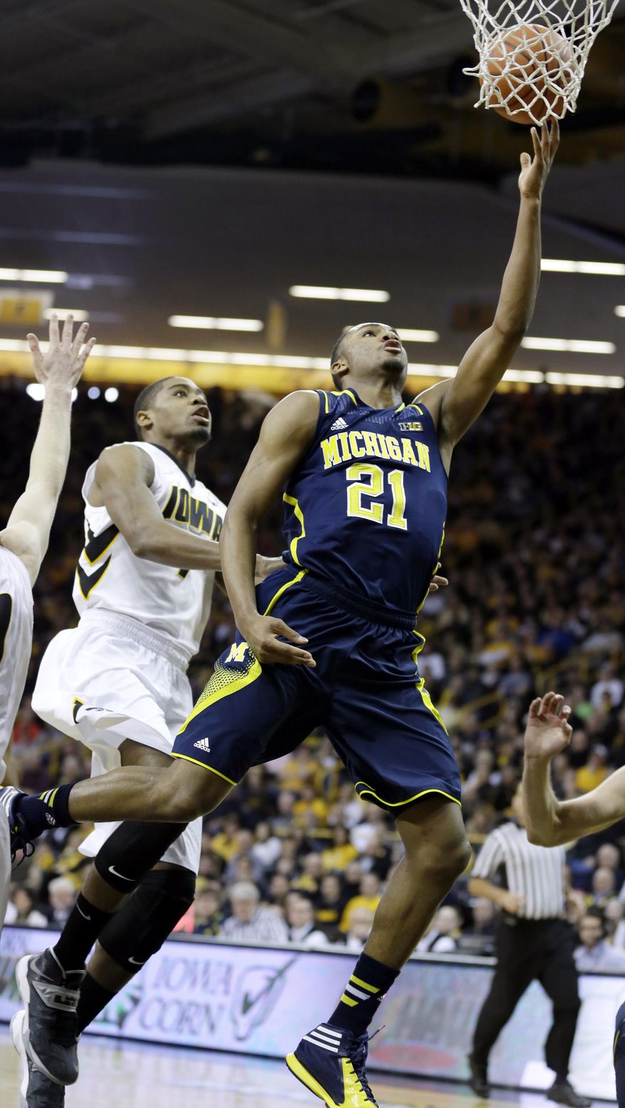 Michigan guard Zak Irvin drives to the basket past Iowa forward Melsahn Basabe, left, during the first half of an NCAA college basketball game, Saturday, Feb. 8, 2014, in Iowa City, Iowa. (AP Photo/Charlie Neibergall)