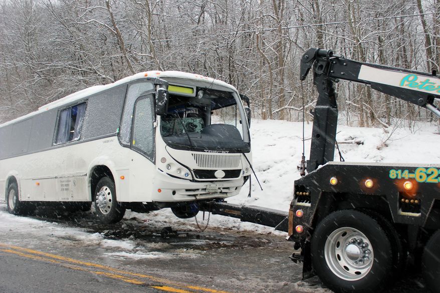A bus is towed after the driver lost control and struck an embankment on Route 220 in Cumberland Valley Twp., Pa., Sunday, Feb. 9, 2014, according to the police. More than 20 passengers were injured in the crash. (AP Photo/Bedford Gazette, Bridgett Weaver)