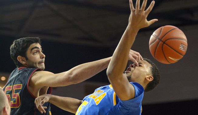 Southern California center Omar Oraby, left, pokes UCLA guard Kyle Anderson in the face after blocking his shot during the first half of an NCAA college basketball game, Saturday, Feb. 8, 2014, in Los Angeles. (AP Photo/Mark J. Terrill)