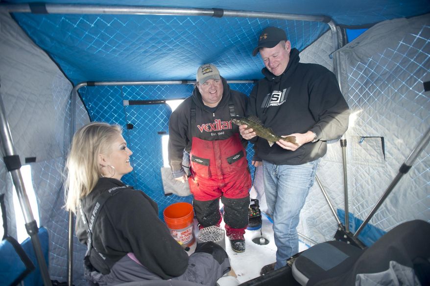 Steve Dahl, owner of the Perch Patrol, checks in with clients Lisa and Matt Johnson of Forest Lake, Minn. Matt is holding a walleye, Saturday, Feb. 8, 2014.   (AP Photo/Jackie Lorentz)