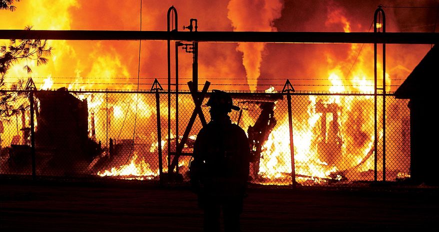 A firefighter is silhouetted by the flames that consumed a maintenance building early Sunday Feb. 9, 2014, at the Winchester Ammunition Plant in East Alton, Ill.  The first of several high pressure steam pipes which burst in the intense heat, begins to spew, background. Despite the efforts of more than 25 firefighters from as many as seven local fire departments, the building was a total loss. The cause is under investigation. (AP Photo/The Telegraph,John Badman)  THE NEWS-DEMOCRAT AND THE POST-DISPATCH OUT