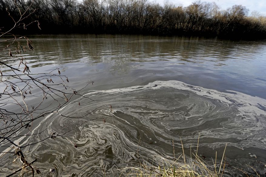 In this Wednesday, Feb. 5, 2014 photo, signs of coal ash swirl in the water in the Dan River in Danville, Va. Duke Energy estimates that up to 82,000 tons of coal ash has been released from a break in a 48-inch storm water pipe at the Dan River Power Plant in Eden N.C.Over the last year, environmental groups have tried three times to use the federal Clean Water Act to force Duke Energy to clear out leaky coal ash dumps. Each time, the N.C. Department of Environment and Natural Resources has effectively halted the lawsuit by intervening at the last minute to assert its own authority to take enforcement action. In two cases, the state has proposed modest fines but no requirement that the nation’s largest electricity provider actually clean up the coal ash ponds. The third case is pending. (AP Photo/Gerry Broome)