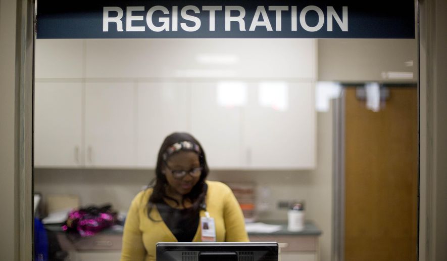 A worker is seen behind the registration window of the emergency room at Grady Memorial Hospital in Atlanta on Jan. 24, 2014. (Associated Press) **FILE**