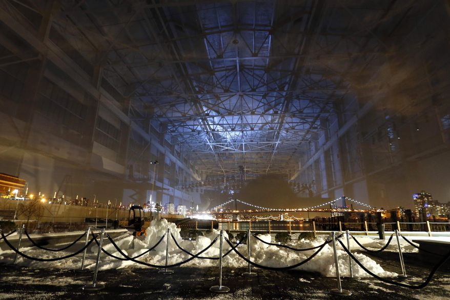 The interior of the Brooklyn Navy Yard's Duggal Greenhouse is reflected in a window looking out at the Williamsburg Bridge before the Alexander Wang Fall 2014 show during Fashion Week in New York, Saturday, Feb. 8, 2014. (AP Photo/Jason DeCrow)