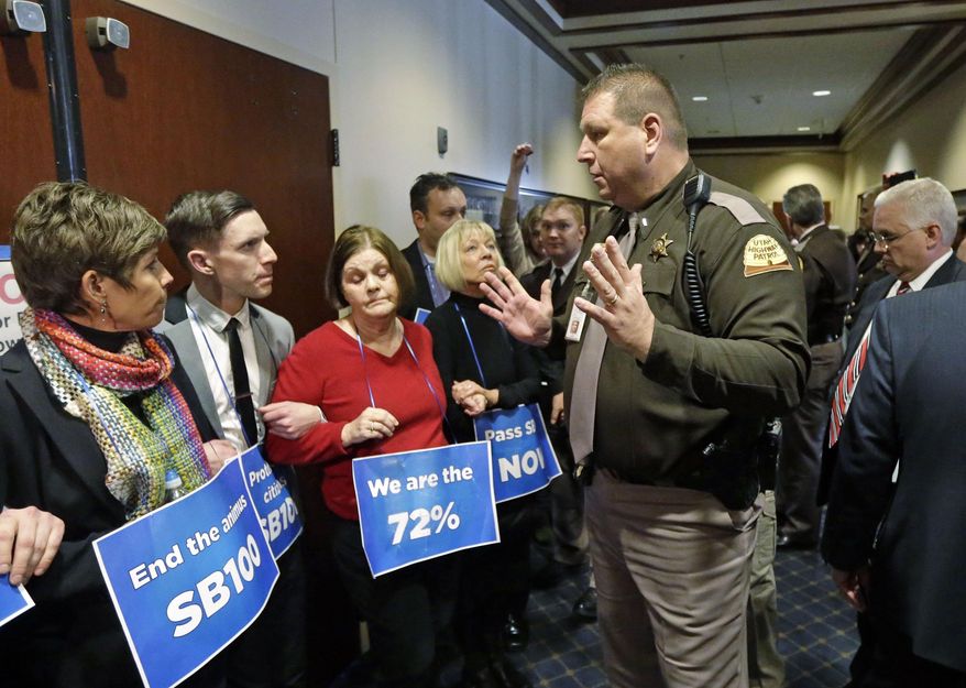 A Utah Highway Patrol trooper informs protesters who blocked the doors to the higher education committee hearing of their arrest Monday, Feb. 10, 2014, at the Utah State Capitol, in Salt Lake City. The protesters called for a statewide anti-discrimination law that protects sexual or gender orientation. (AP Photo/Rick Bowmer)
