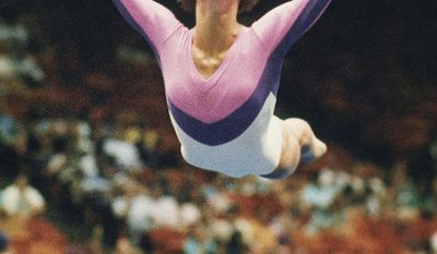 FILE - In this July 1988 file photo, U.S. gymnast Phoebe Mills flies through the air as she performs her floor exercise at the U.S. Gymnastics Championships in Houston, Texas. Mills used to flip for Olympic medals. These days, she decides who wins them. The 1988 U.S. gymnastics champion and Olympic bronze medalist is working in the snowboarding judging booth at the Sochi Games, giving marks in both the halfpipe and slopestyle contests at Rosa Khutor Extreme Park.  (AP Photo/David Breslauer, File)