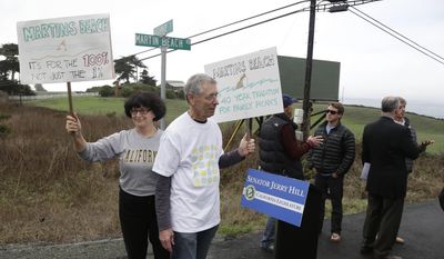 Julie Graves, left, of Albany, Calif., and Chris Adams, second from left, of Berkeley, Calif., hold up signs in support of a beach access bill that Democratic state Sen. Jerry Hill introduced near Martin's Beach Monday, Feb. 10, 2014, in Half Moon Bay, Calif. A bill seeking to re-establish public access to a popular Northern California beach that was closed off after a Silicon Valley billionaire bought the adjacent land was introduced on Monday.  Hill said his bill would require the State Lands Commission to negotiate with Sun Microsystems Inc. co-founder Vinod Khosla to purchase some or all of his land at Martin's Beach. Adams and Graves are part of families that have gone to the beach for picnics for over 40 years. (AP Photo/Eric Risberg)