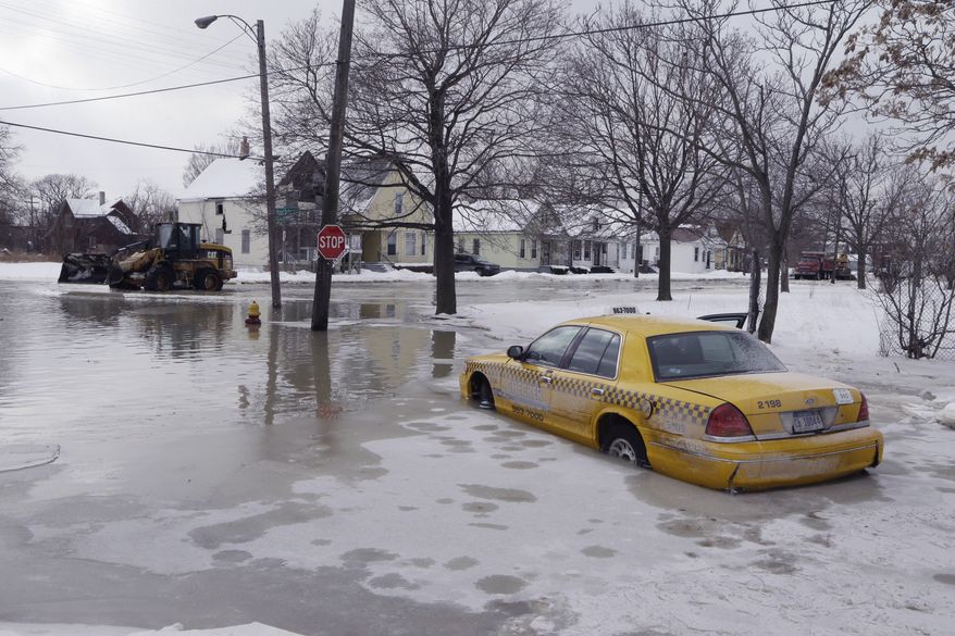 A taxi cab is surrounded by water on a flooded street after a water main break in Detroit on Tuesday, Feb. 11, 2014. The broken water main flooded a several-block area in southwest Detroit, trapping several cars. (AP Photo/Carlos Osorio)