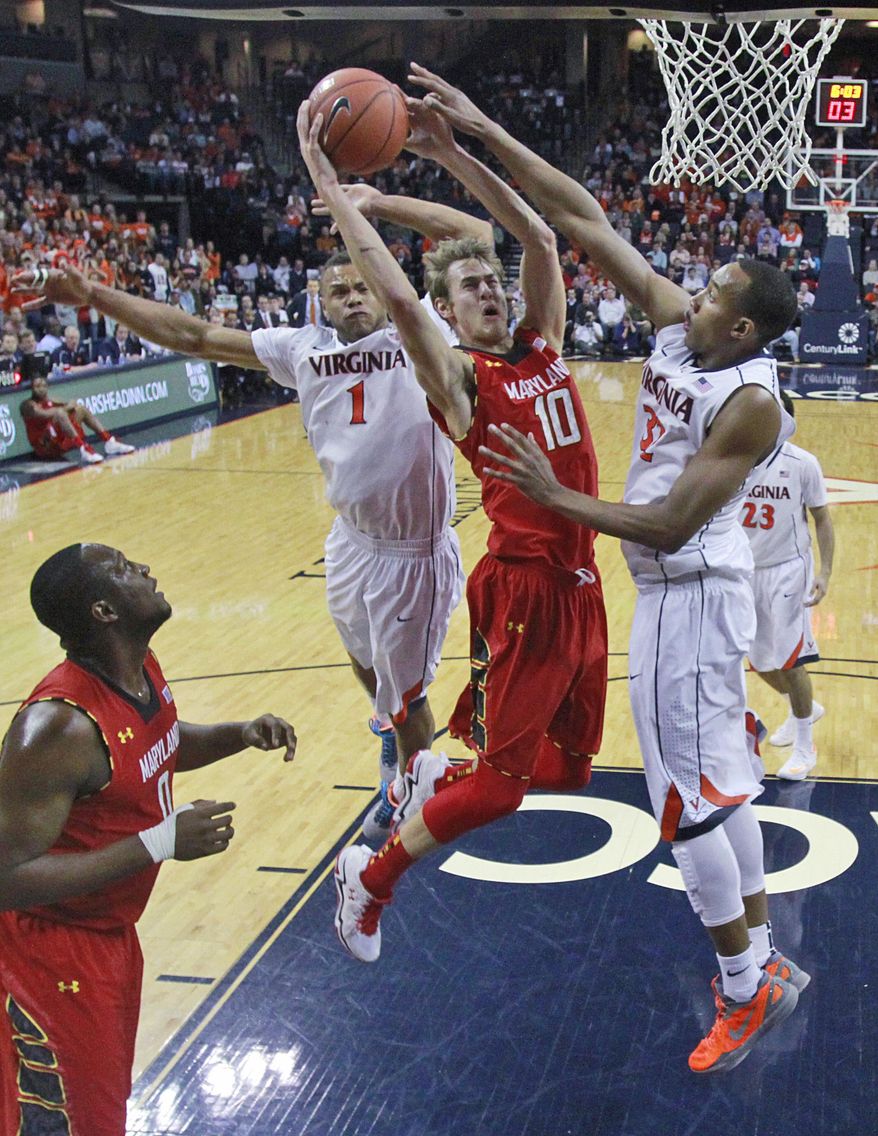 Virginia guard Justin Anderson (1) and Virginia forward Darion Atkins, right, combine to block a shot by Maryland forward Jake Layman (10) during the second half of an NCAA college basketball game in Charlottesville, Va., Monday, Feb. 10, 2014. Virginia won the game 61-53. (AP Photo/Steve Helber)