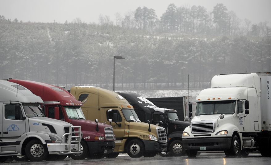 Tractor trailer rigs parked at a gas station are covered with snow about 40 miles north of metro Atlanta, in Emerson, Ga., on Tuesday, Feb. 11, 2014. President Obama signed an emergency declaration for Georgia as the winter storm hit the state Tuesday. (AP Photo/David Tulis)