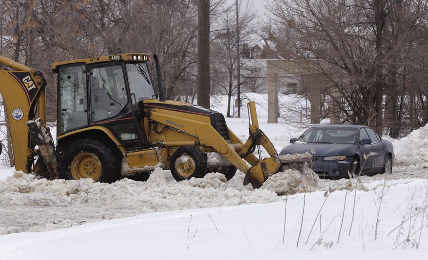 Work crews clear ice off the road as water continues to spew from a broken water main in Detroit on Tuesday, Feb. 11, 2014. The broken water main flooded a several-block area in southwest Detroit, trapping several cars. (AP Photo/Carlos Osorio)