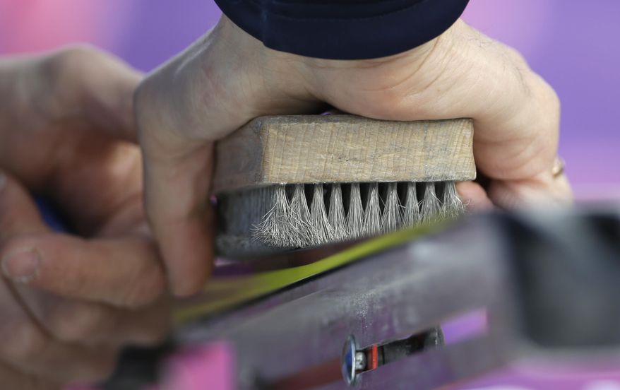 A waxing technician brushes a ski during the cross-country sprint competitions at the 2014 Winter Olympics, Tuesday, Feb. 11, 2014, in Krasnaya Polyana, Russia. (AP Photo/Gregorio Borgia)
