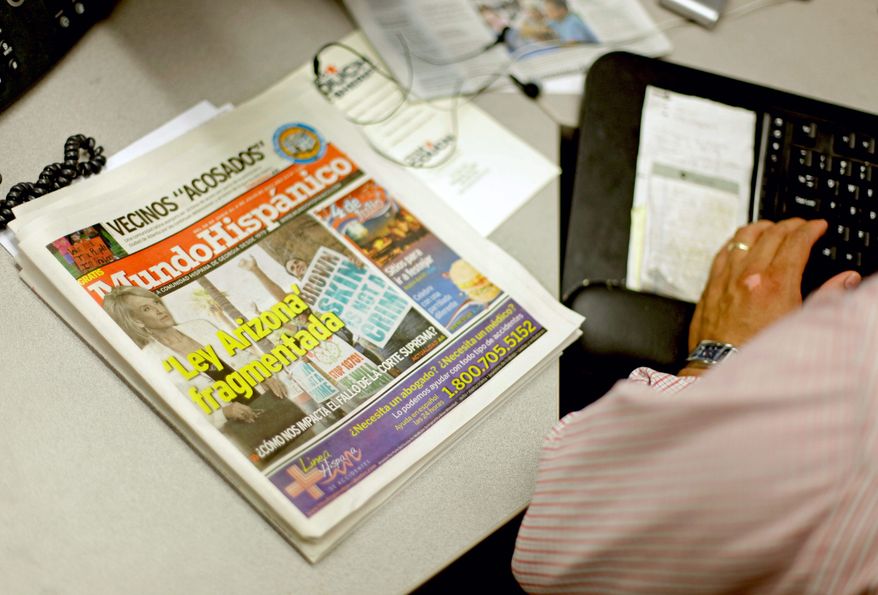 A copy of the Mundo Hispanico newspaper with a headline on the Arizona immigration law sits next to reporter Mario Guevara as he works in the newsroom Thursday, July 5, 2012, in Norcross, Ga. The reporter for Georgia's largest Spanish-language newspaper who frequently writes about immigration issues has recently found himself caught up in his own immigration drama. (AP Photo/David Goldman)
