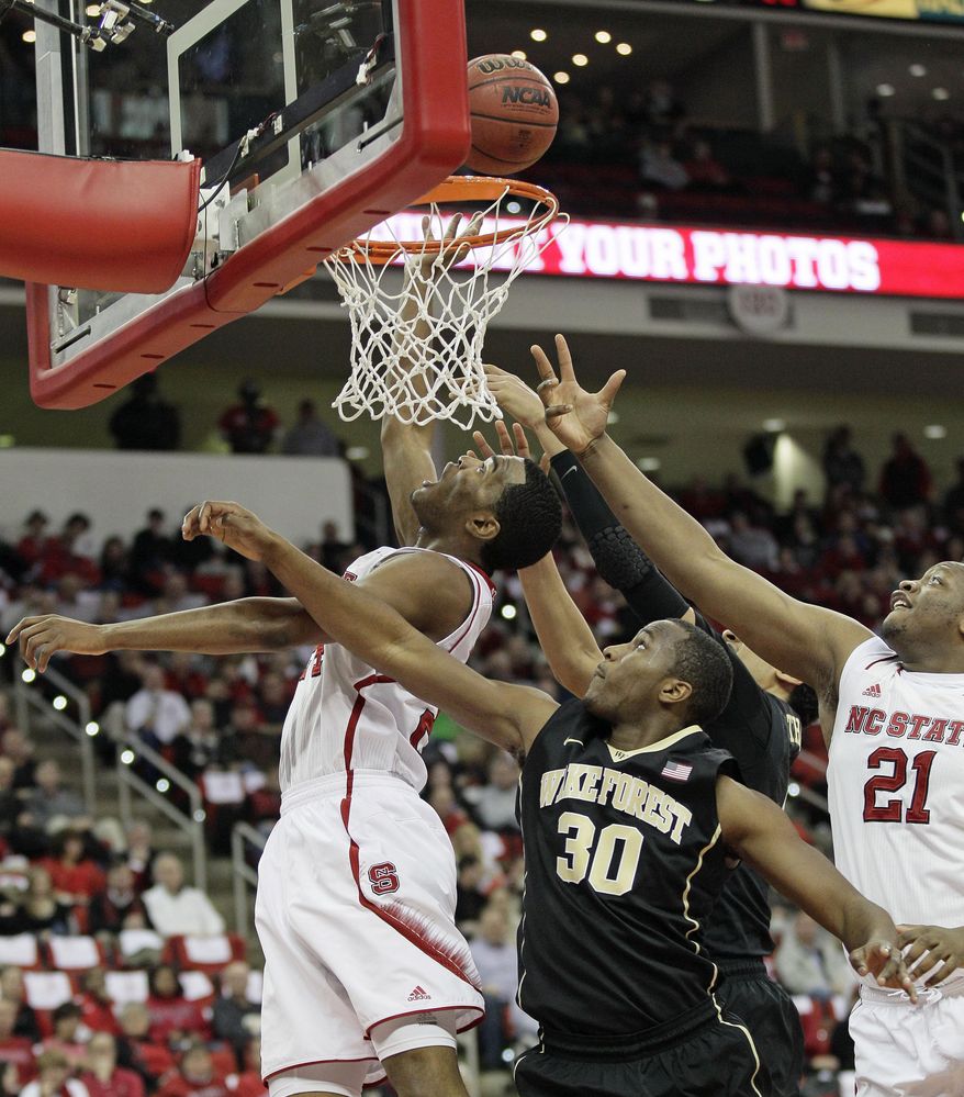 North Carolina State's T.J. Warren drives under the basket as Wake Forest's Travis McKie (30) and North Carolina State's Beejay Anya (21) reach for the ball during the first half of an NCAA college basketball game in Raleigh, N.C., Tuesday, Feb. 11, 2014. (AP Photo/Gerry Broome)