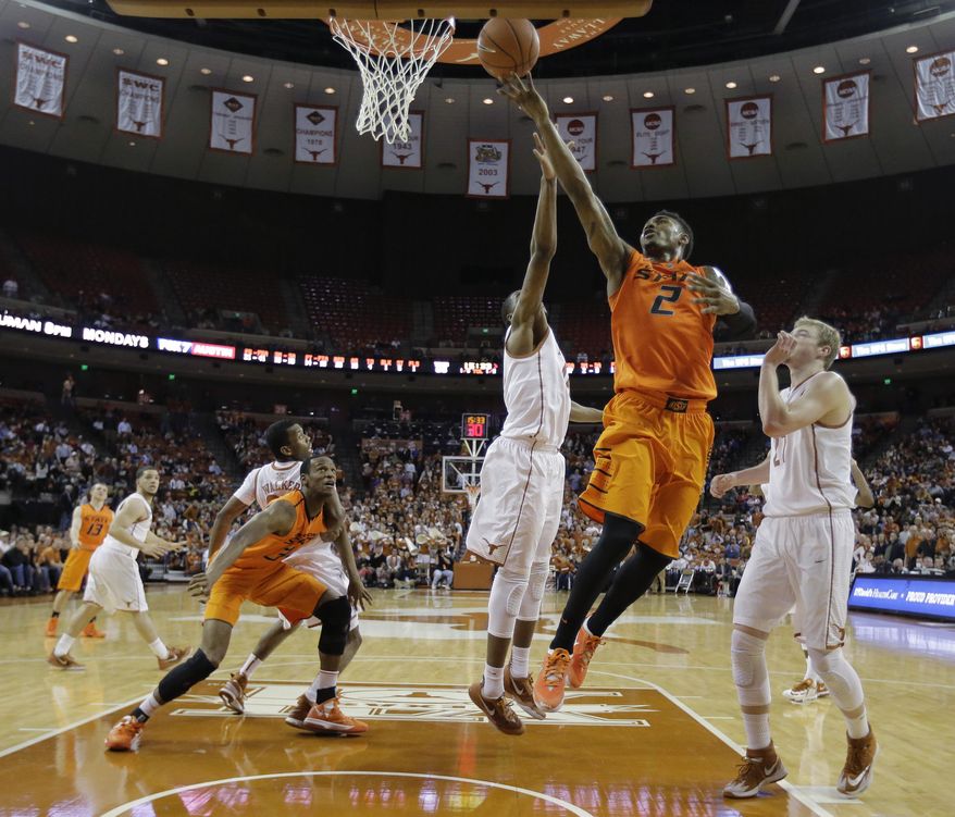 Oklahoma State's Le'Bryan Nash (2) drives between Texas' Prince Ibeh (44) and Connor Lammert (21) to score during the second half on an NCAA college basketball game, Tuesday, Feb. 11, 2014, in Austin, Texas. Texas won 87-68. (AP Photo/Eric Gay)