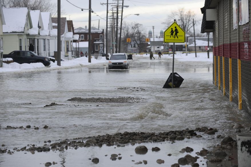 Water floods a street after a water main break in Detroit on Tuesday, Feb. 11, 2014. The broken water main flooded a several-block area in southwest Detroit, trapping several cars. (AP Photo/Detroit News, David Coates)