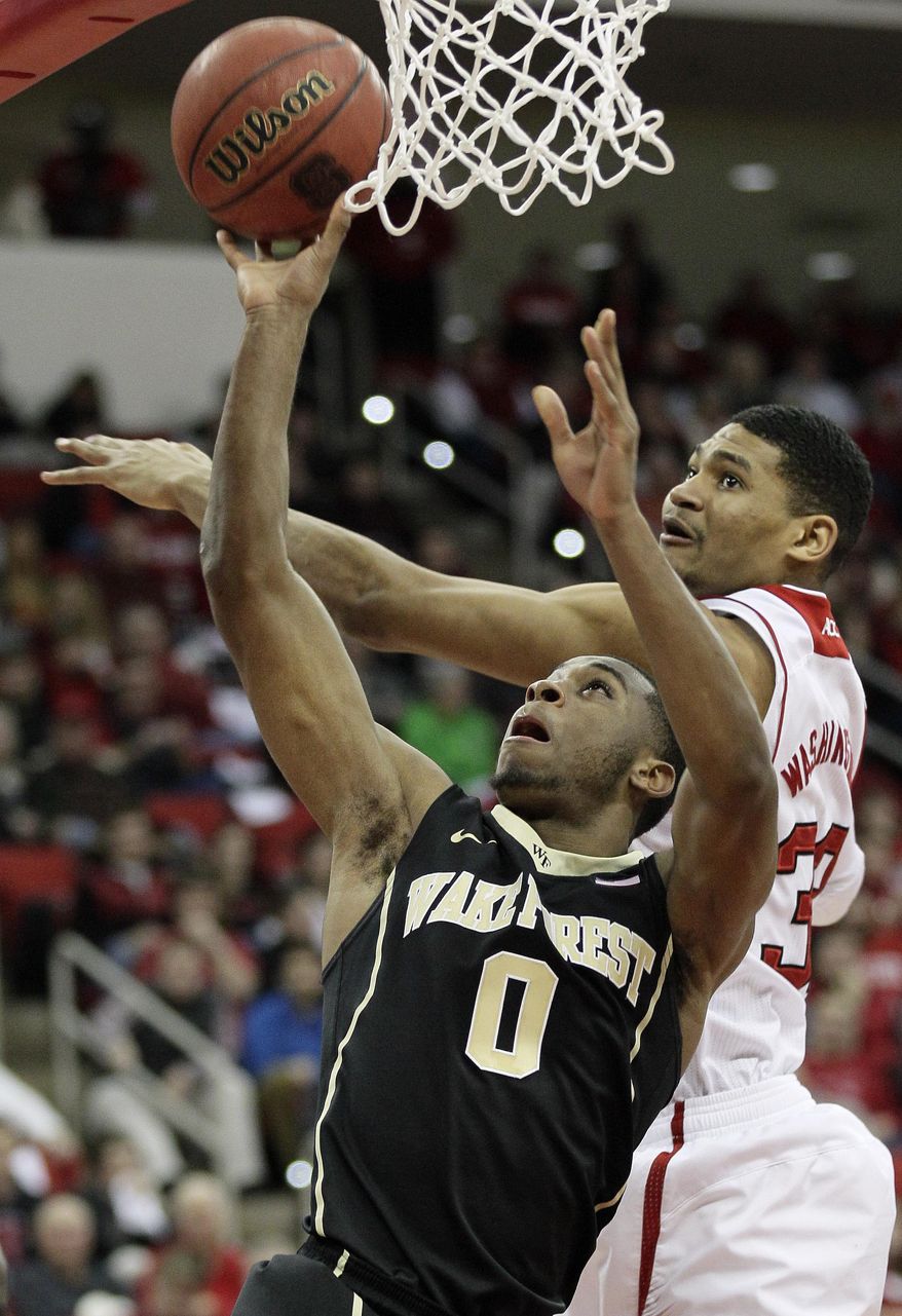 Wake Forest's Codi Miller-McIntyre (0) shoots as North Carolina State's Kyle Washington defends during the second half of an NCAA college basketball game in Raleigh, N.C., Tuesday, Feb. 11, 2014. North Carolina State won 82-67. (AP Photo/Gerry Broome)