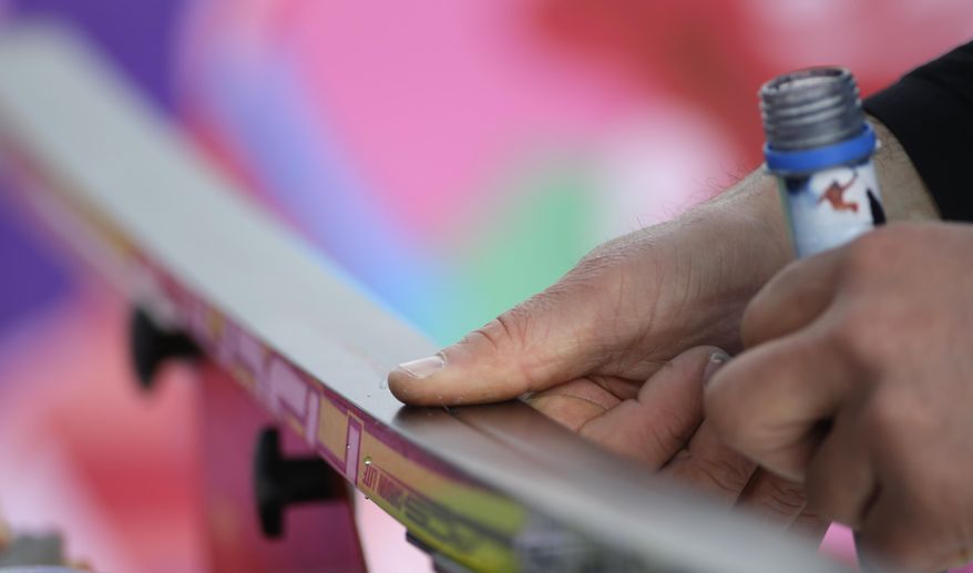 A waxing technician works on a ski during the cross-country sprint competitions at the 2014 Winter Olympics, Tuesday, Feb. 11, 2014, in Krasnaya Polyana, Russia. (AP Photo/Gregorio Borgia)