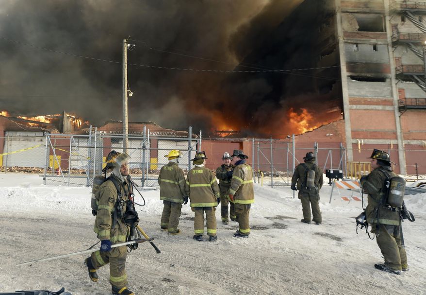 Firefighters work the scene of a fire at an abandoned commercial building on Detroit's east side, Tuesday, Feb. 11, 2014. Battalion Chief Richard Wright says a firefighter was injured when he fell at least 10 feet from an aerial lift to ground after being hit by flying bricks. Wright says the six-story building has been burning for about a week and the department's strategy is to spray water on it whenever possible. (AP Photo/Carlos Osorio)