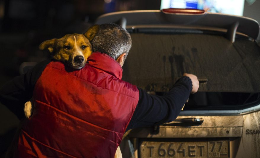 Animal activist Igor Airapetian carries a stray dog to his car brought out of Sochi by fellow activist at a rendezvous point 120 kilometers away from the Olympic area in the early morning hours of Tuesday, Feb. 11, 2014, in Tuapse, Russia. Airapetian is one of a dozen people in the emerging movement of animal activists in Sochi alarmed by reports that the city has contracted the killing of thousands of stray dogs before and during the Olympic Games. Stray dogs are a common sight on the streets of Russian cities, but with massive construction in the area the street dog population in Sochi and the Olympic park has soared. Useful as noisy, guard dogs, workers feed them to keep them nearby and protect buildings. They soon lose their value and become strays. Tonight, a few dogs will be taken on their way to a new life in Moscow. (AP Photo/David Goldman)