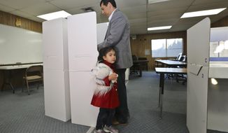 San Diego mayoral candidate David Alvarez cast his ballot as a his daughter, Izel, holds onto his leg at a polling location in the Logan Heights neighborhood where Alvarez grew up and still lives Tuesday, Feb. 11, 2014 in San Diego. (AP Photo/Lenny Ignelzi)