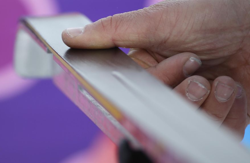 A waxing technician works on a ski during the cross-country sprint competitions at the 2014 Winter Olympics, Tuesday, Feb. 11, 2014, in Krasnaya Polyana, Russia. (AP Photo/Gregorio Borgia)