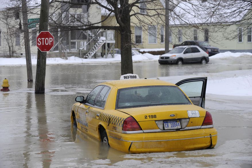 A taxi cab is surrounded by water on a flooded street after a water main break in Detroit on Tuesday, Feb. 11, 2014. The broken water main flooded a several-block area in southwest Detroit, trapping several cars. (AP Photo/Detroit News, David Coates)