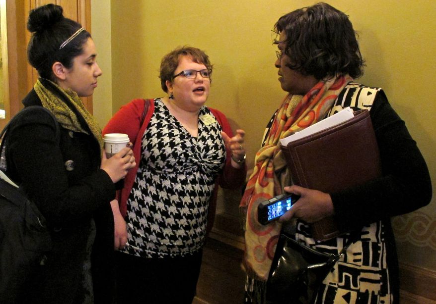 Ariana Nasrazadani, left, an intern for Planned Parenthood of Kansas and Mid-Missouri, and Elise Higgins, center, a Planned Parenthood lobbyist, confer with Kansas state Rep. Valdenia Winn, right, a Kansas City Democrat, following a legislative committee meeting on abortion legislation, Tuesday, Feb. 11, 2014, at the Statehouse in Topeka, Kan. Planned Parenthood is officially neutral on a bill making technical changes in anti-abortion laws. (AP Photo/John Hanna)