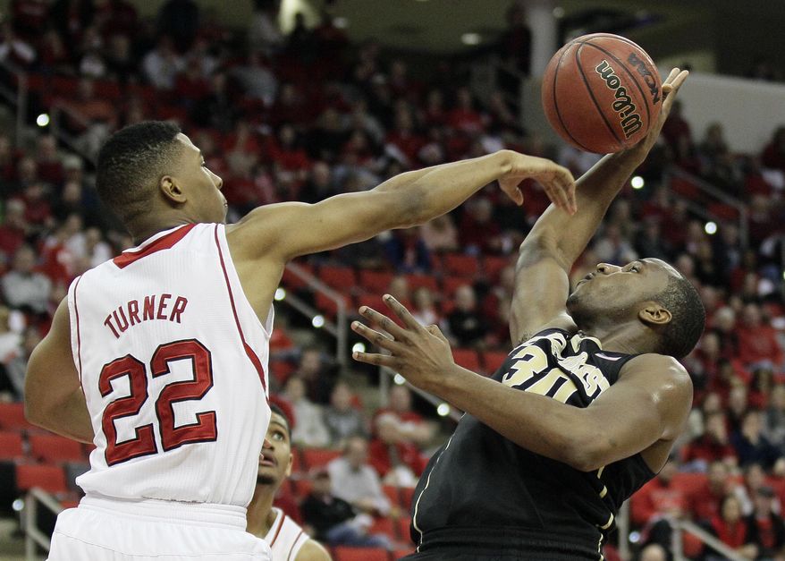 North Carolina State's Ralston Turner (22) blocks Wake Forest's Travis McKie during the second half of an NCAA college basketball game in Raleigh, N.C., Tuesday, Feb. 11, 2014. North Carolina State won 82-67. Turner was called for a foul on the play. (AP Photo/Gerry Broome)