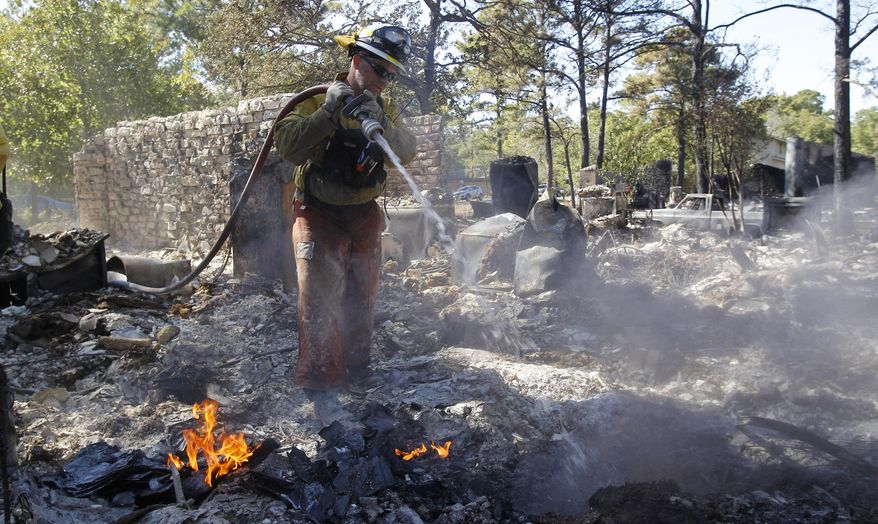 File - In this Sept. 8, 2011 file photo, a firefighter sprays a hot spot at a home destroyed by wildfires, in Bastrop, Texas. Forestry officials say this year's wildfire threat will be highest in only some parts of Texas but even that danger isn't close to what happened three years ago when blazes burned more than 2,700 homes and blackening about 6,200 square miles. (AP Photo/Eric Gay, File)