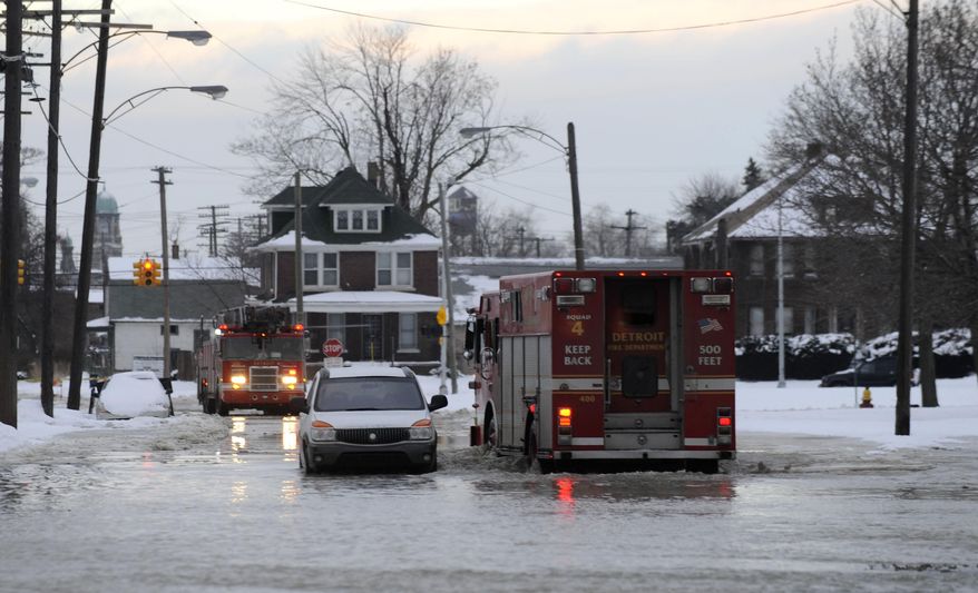 Detroit firefighters drive through a flooded street after a water main break in Detroit on Tuesday, Feb. 11, 2014. The broken water main flooded a several-block area in southwest Detroit, trapping several cars. (AP Photo/Detroit News, David Coates)