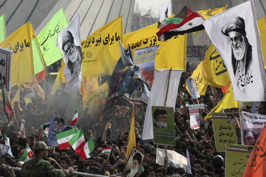 Iranians burn representations of British, Israeli, and U.S. flags, as they hold pro-government placards and portraits of supreme leader Ayatollah Ali Khamenei during an annual rally commemorating anniversary of the 1979 Islamic revolution, at the Azadi, 'Freedom' Square in Tehran, Iran, Tuesday, Feb. 11, 2014. Tuesday marks the 35th anniversary of the revolution that toppled the pro-U.S. Shah Mohammad Reza Pahlavi and brought Islamists to power. The banners in yellow read, "we are ready for the great battle." (AP Photo/Vahid Salemi)
