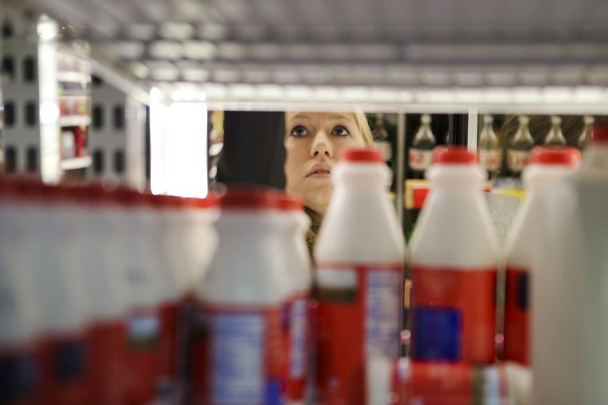 Jennifer Poulos reaches in the dairy shelves, Monday, Feb. 10, 2014, in Atlanta.On Monday, officials were quick to act as the winter weather zeroed in. Before a single drop of freezing rain or snow fell, Georgia Gov. Nathan Deal had declared a state of emergency for nearly a third of the state, schools canceled classes and workers were told to stay home. (AP Photo/Atlanta Journal-Constitution, John Spink)