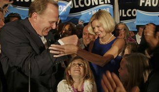 San Diego mayoral candidate Kevin Faulconer reaches for his wife, Katherine, as their daughter looks up from below after Faulconer addressed his supporters at a rally Tuesday, Feb. 11, 2014, in San Diego. (AP Photo/Lenny Ignelzi)