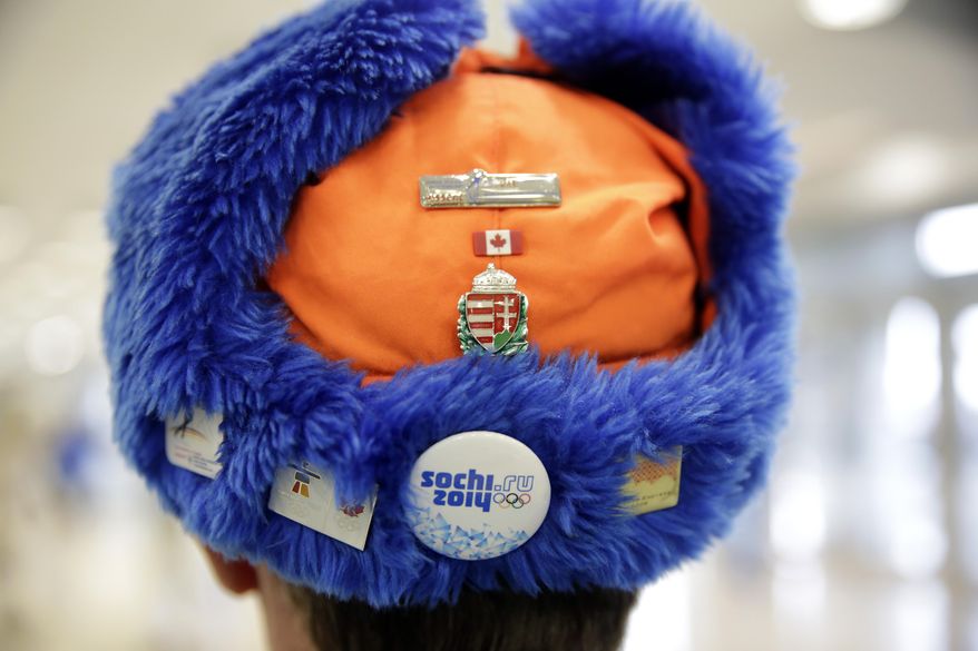 A skating fan sports a cap with Olympic pins on it prior to the start of the women's 500-meter speedskating race at the Adler Arena Skating Center at the 2014 Winter Olympics, Tuesday, Feb. 11, 2014, in Sochi, Russia. (AP Photo/Matt Dunham)