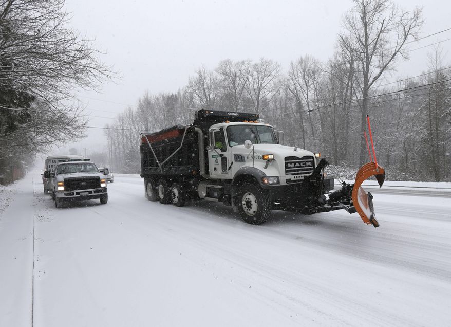 A truck carrying salt and slag drives along a near empty road as a winter storm moves into the area in Charlotte, N.C., Wednesday, Feb. 12, 2014. (AP Photo/Chuck Burton)