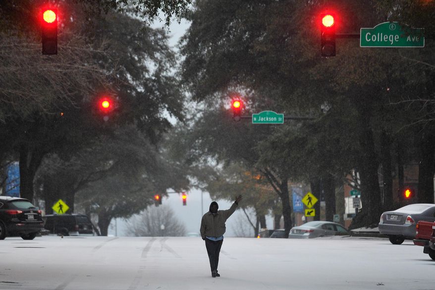 A man waves while walking along the center of Clayton Street on Wednesday, Feb. 12, 2014, in Athens, Ga. A combination of sleet, snow and freezing rain was expected to coat power lines and tree branches with more than an inch of ice between Atlanta and Augusta. (AP Photo/Athens Banner-Herald, AJ Reynolds) MAGS OUT; TV OUT: MANDATORY CREDIT