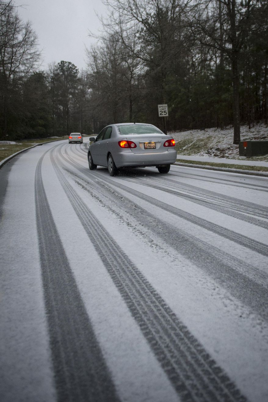 Motorists drive on a road covered in snow and ice on Wednesday, Feb. 12, 2014, in Johns Creek, Ga. Across the South, winter-weary residents woke up Wednesday to a region encased in ice, snow and freezing rain, with forecasters warning that the worst of the potentially "catastrophic" storm is yet to come. From Texas to the Carolinas and the South's business hub in Atlanta, roads were slick with ice, tens of thousands were without power, and a wintry mix fell in many areas. (AP Photo/John Amis)