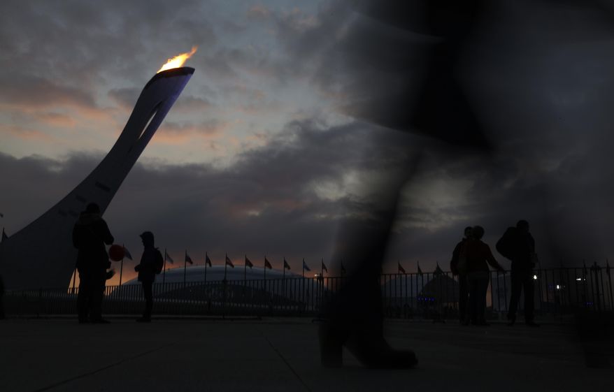 Spectator walk past the Olympic Cauldron as the sun sets at the 2014 Winter Olympics, Tuesday, Feb. 11, 2014, in Sochi, Russia. (AP Photo/Morry Gash)