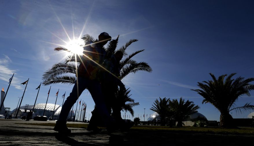 Visitors to the Olympic Park pass by palm trees on a warm sunny dat at the 2014 Winter Olympics, Wednesday, Feb. 12, 2014, in Sochi, Russia. (AP Photo/David J. Phillip )