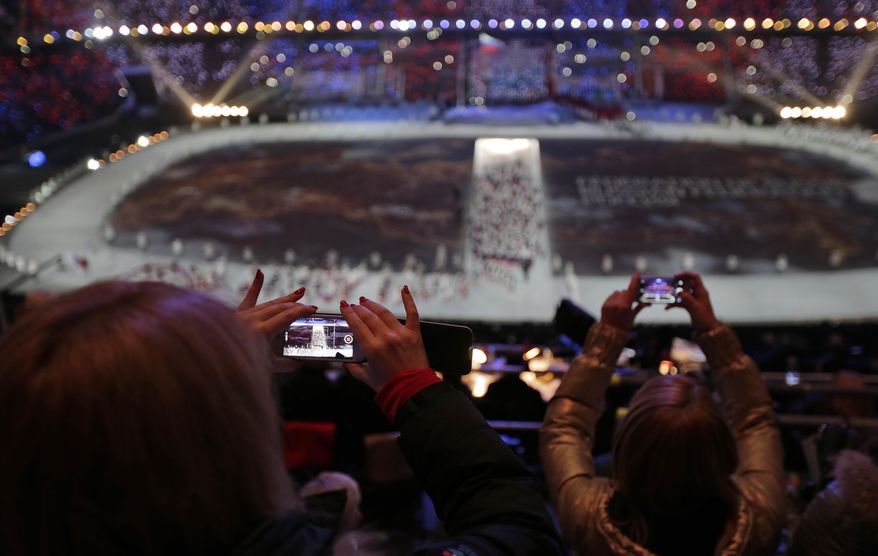 FILE - In this Friday, Feb. 7, 2014, file photo, a spectator takes a video of the opening ceremony on her mobile phone at the 2014 Winter Olympics in Sochi, Russia. (AP Photo/Charlie Riedel, File)
