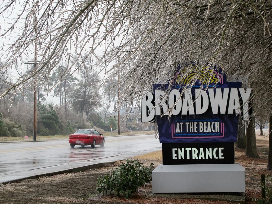 Ice coats trees and the sign at the popular Broadway at the Beach tourist attraction in coastal vacation town of Myrtle Beach, S.C., on Wednesday, Feb. 12, 2014 as a winter storm moves through South Carolina. The storm caused numerous traffic accidents and killed electric power to tens of thousands statewide. (AP Photo/Bruce Smith)