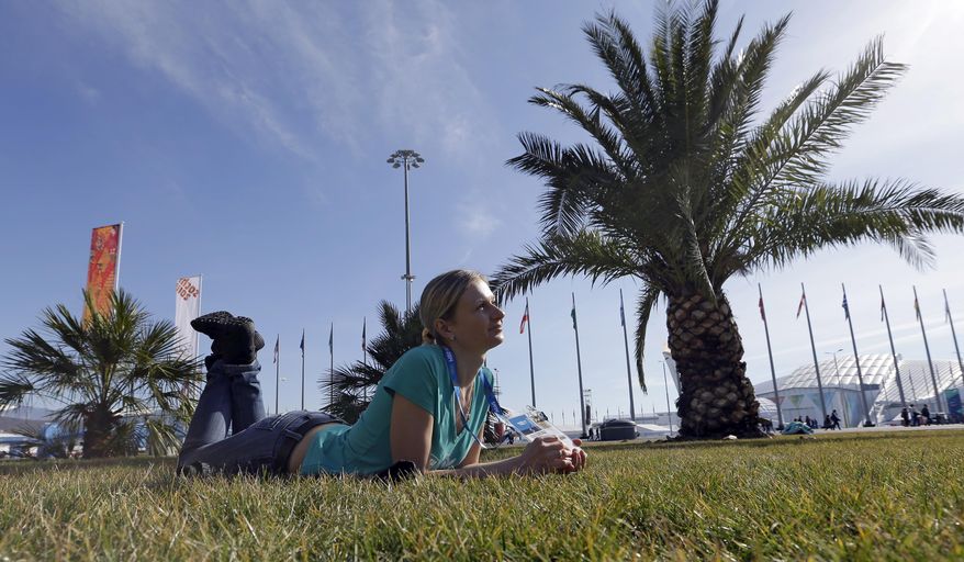 Oxsana Kharitonova lyes on the grass while posing for a photograph with friends on a sunny warm day at the 2014 Winter Olympics, Wednesday, Feb. 12, 2014, in Sochi, Russia. (AP Photo/David J. Phillip )