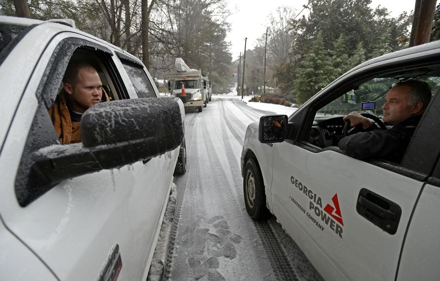 Power company crew members prepare to work on a downed power line that fell near Emory University after freezing rain, sleet and snow toppled trees and power lines during a winter storm on Wednesday, Feb. 12, 2014, in Atlanta. Over 175,000 residences and businesses statewide were without electricity. (AP Photo/David Tulis)